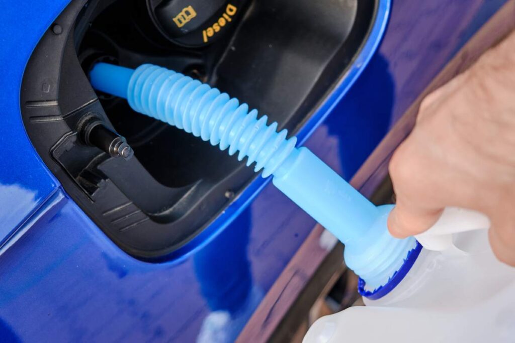 Close up filling of diesel exhaust fluid//adblue from canister into the tank of blue car for reduction of air pollution. Environmental or eco friendly solution.