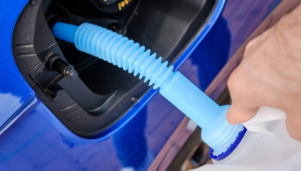 Close up filling of diesel exhaust fluid//adblue from canister into the tank of blue car for reduction of air pollution. Environmental or eco friendly solution.