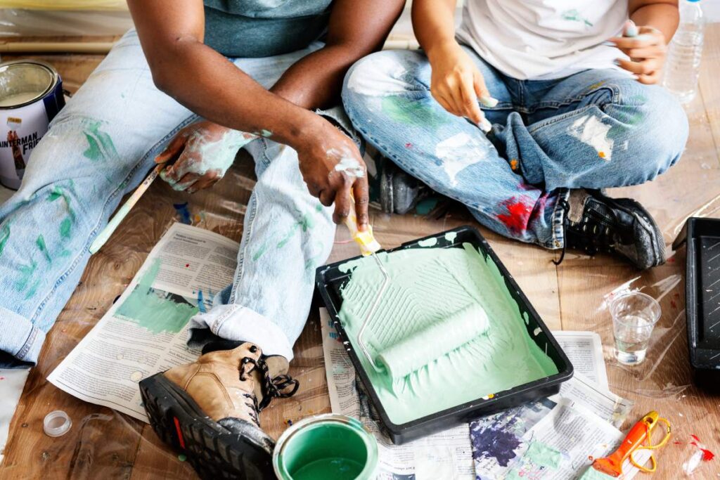 Couple painting house wall