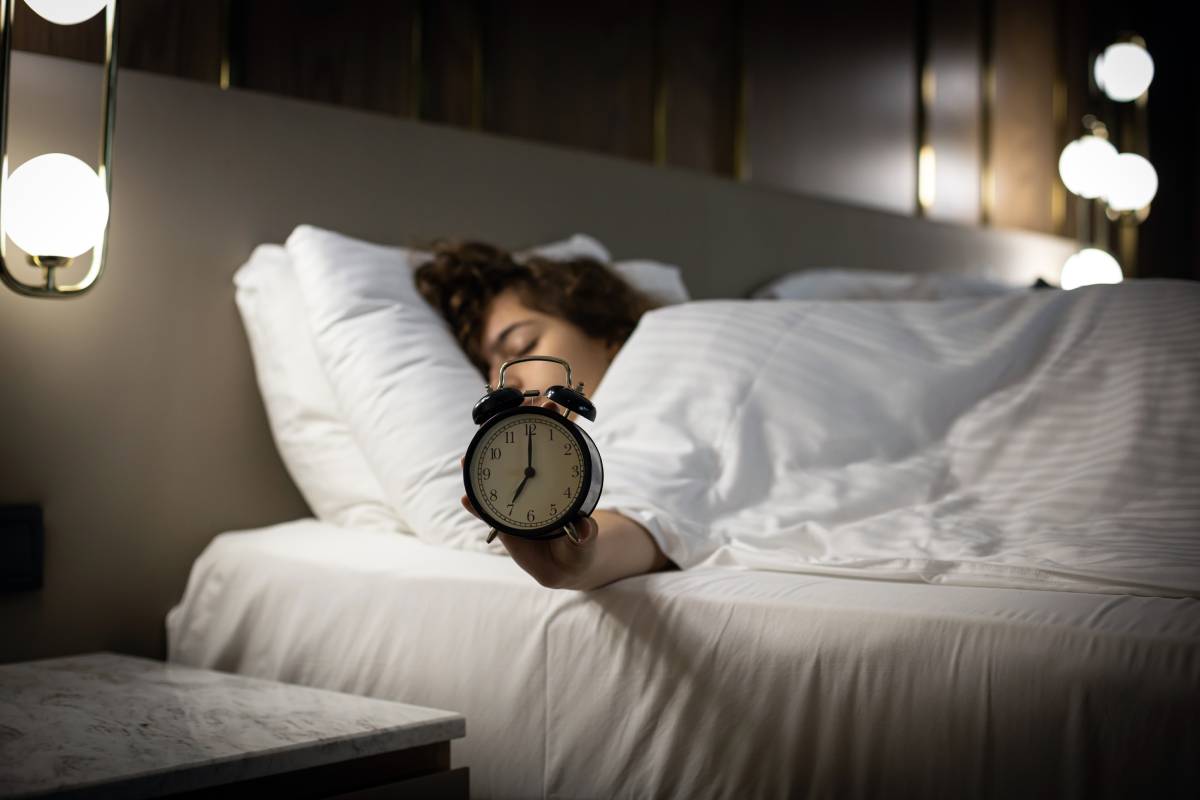 alarm-clock-on-the-bed-with-sleeping-woman-behind-2024-10-17-01-48-49-utc (1)