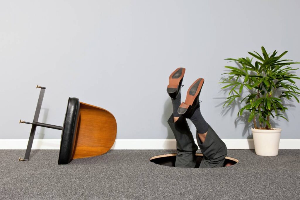 Businessman disappearing through hole in the floor