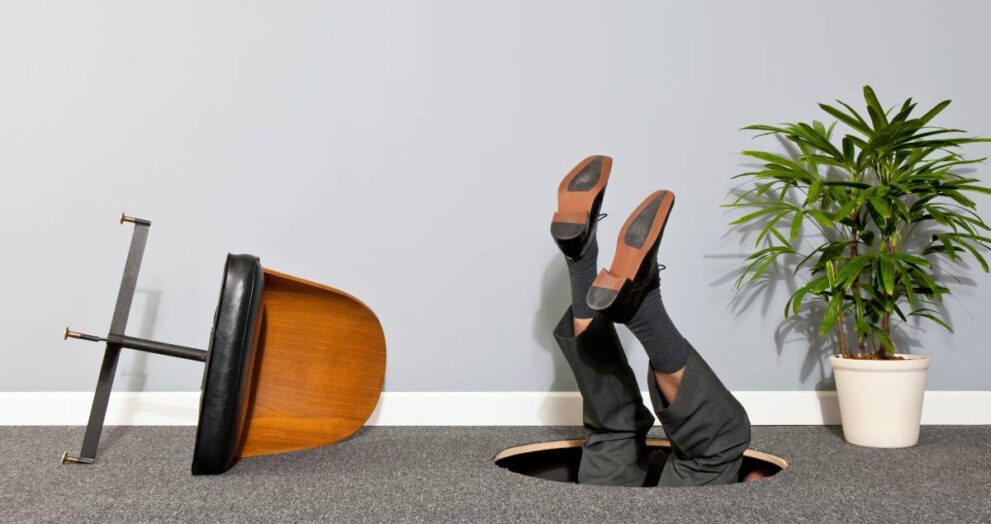 Businessman disappearing through hole in the floor