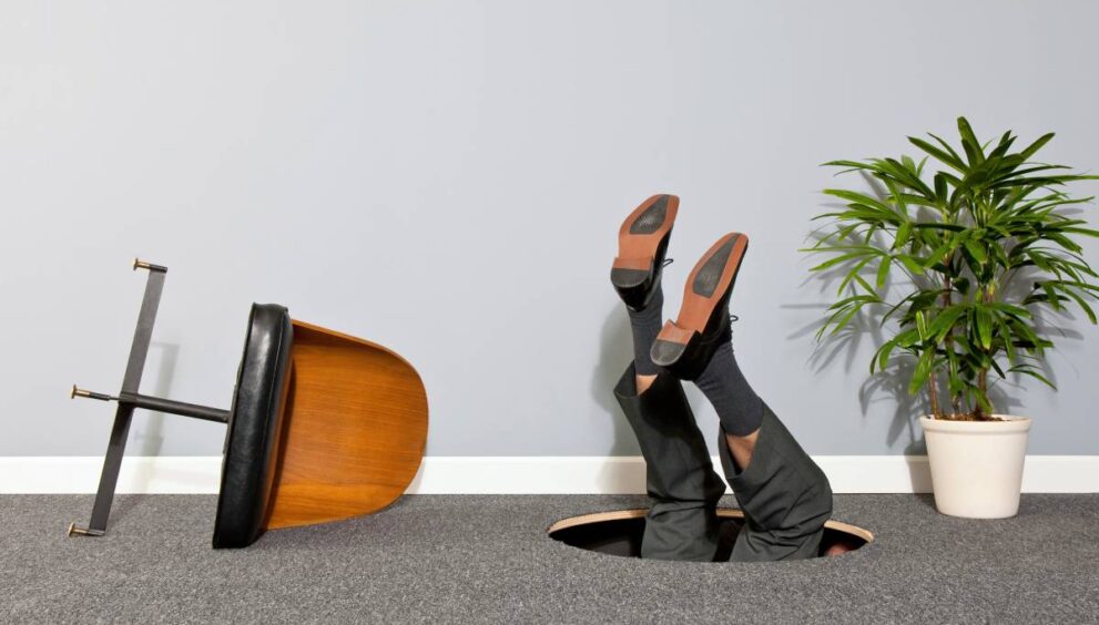 Businessman disappearing through hole in the floor