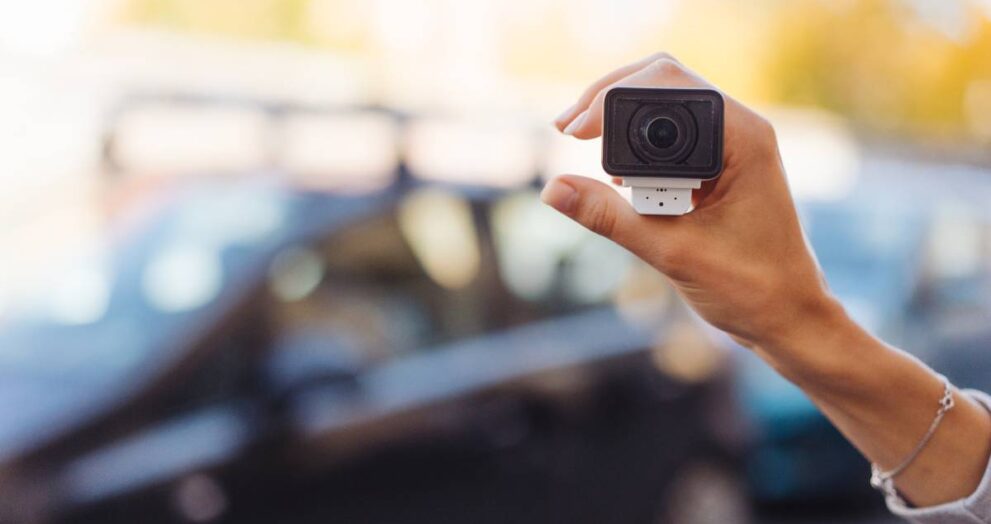 Video camera in a female hand, in the background the street is out of focus